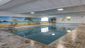 An indoor swimming pool with a beach mural, clear water, and tiled flooring. - Aparthotel Delden (Delden)