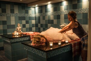 Uma área de spa com mesa de massagem, uma estátua e velas.