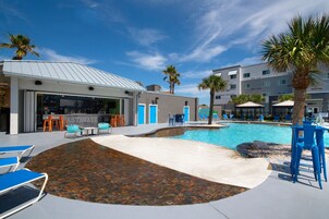 A pool area with lounge chairs, a bar, and a restaurant.