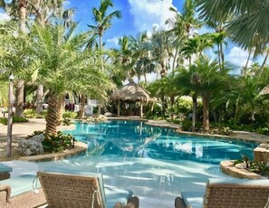 Un espace piscine avec des chaises longues et des palmiers.