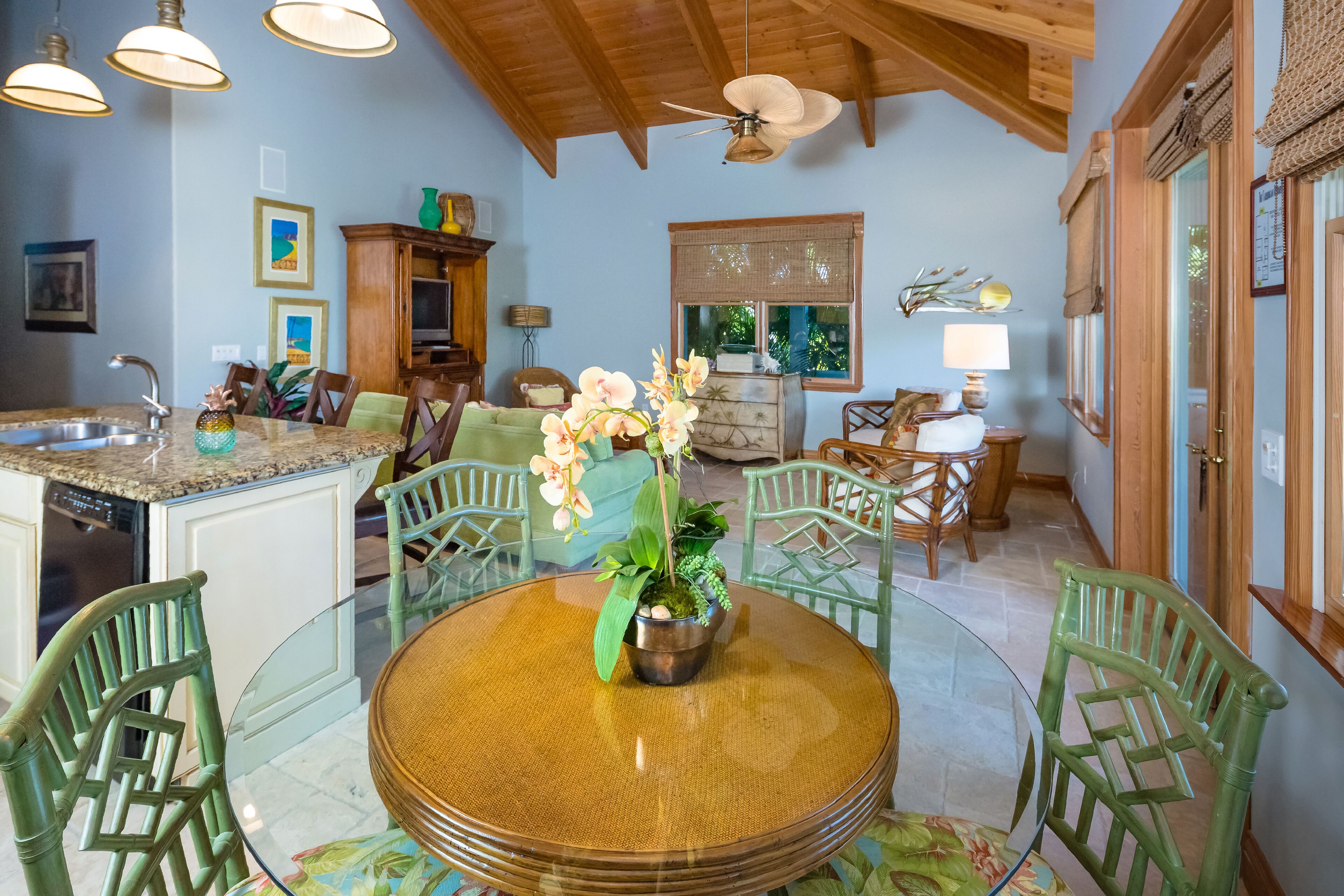 A spacious kitchen with a dining area, wooden ceiling, and a large window.