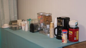 A breakfast bar with various food and drink items, including cereal, coffee, and condiments. - Green Valley Motel (Williamstown)