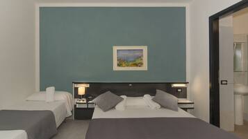 Quarto de hotel com duas camas, um quadro na parede e banheiro visível por uma porta aberta.