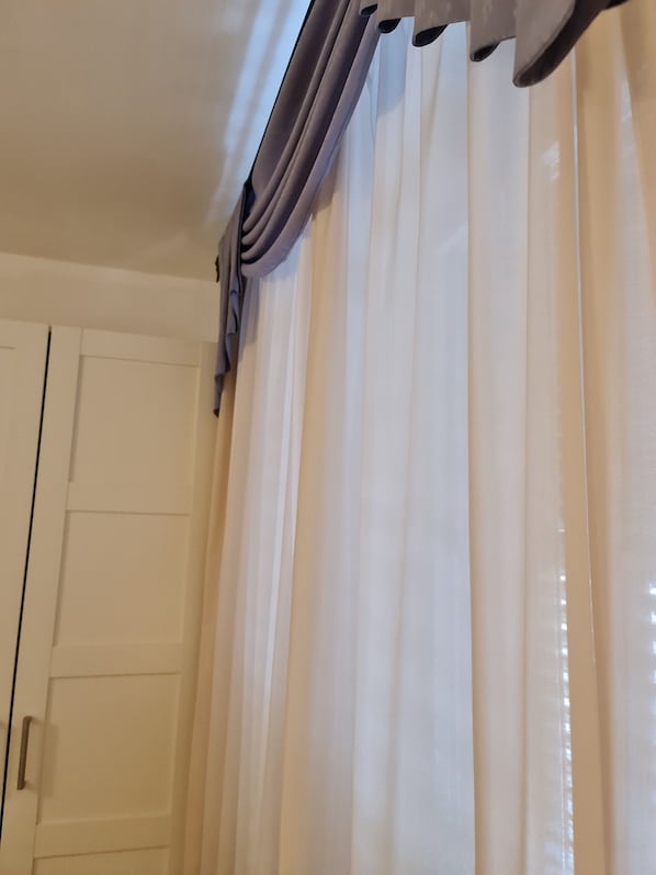 Una habitación con cortinas blancas y una puerta.