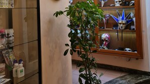 Habitación con una vitrina que contiene artículos de aseo, una placa decorativa y una ventana con máscaras y accesorios.