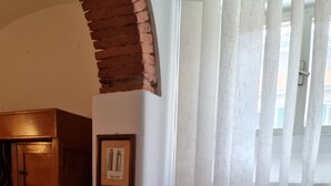 Una habitación con un armario de madera, un cuadro en la pared y una ventana con persianas verticales.