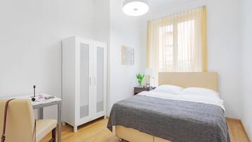 A bedroom with a bed, a desk, a chair, and a wardrobe.