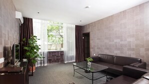 A modern living room with a glass coffee table, leather sofa, and a TV on a stand. - The Art Hotel - Shenzhen (Shenzhen)