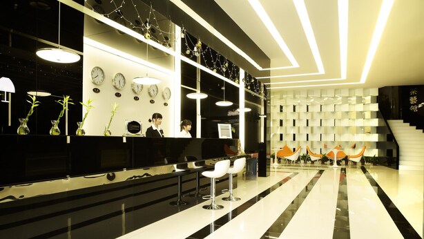 A modern hotel lobby with a reception desk, multiple clocks, and a seating area with chairs. - The Art Hotel - Shenzhen (Shenzhen)