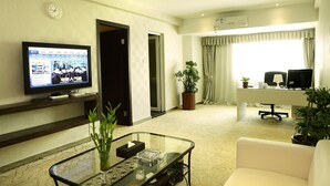 A hotel room with a TV, a glass coffee table, a sofa, a desk with a computer, and a potted plant. - The Art Hotel - Shenzhen (Shenzhen)