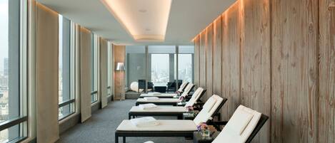 A hotel room with a city view, a wooden wall, and a row of sun loungers.