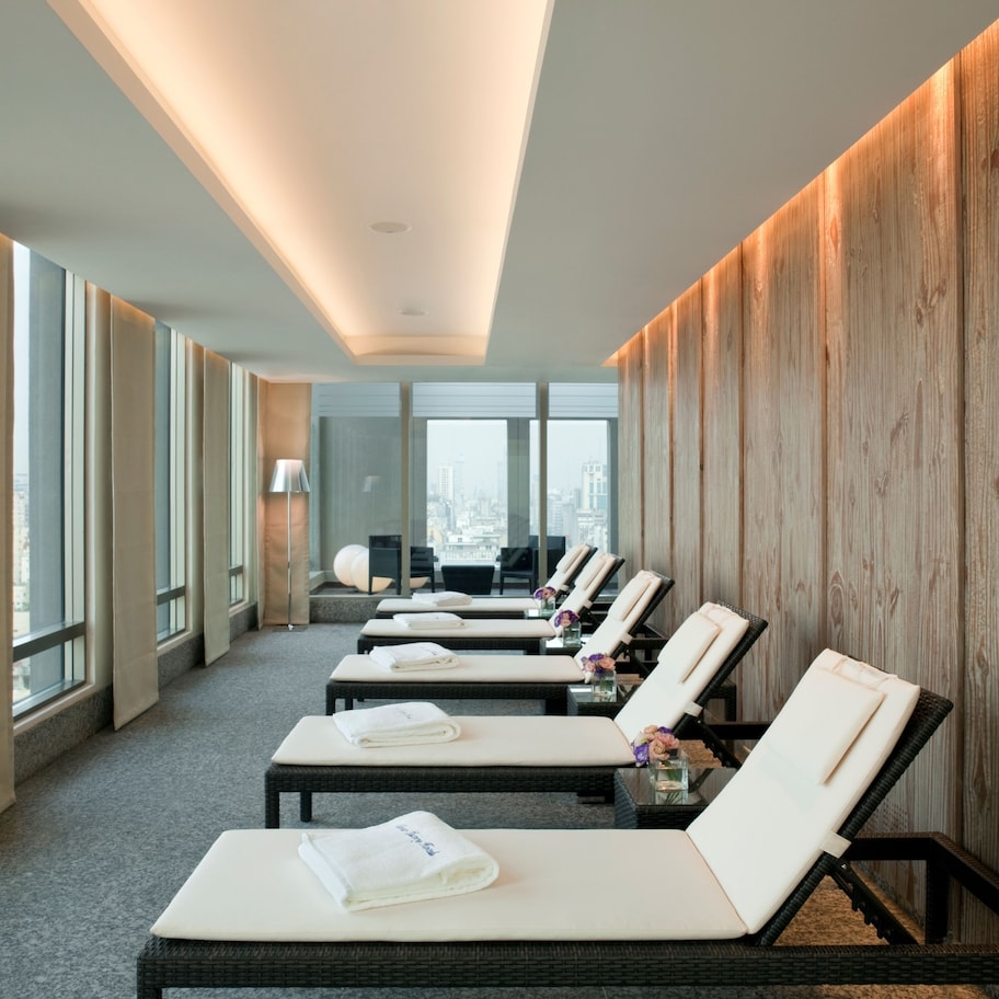 A hotel room with a city view, a wooden wall, and a row of sun loungers.