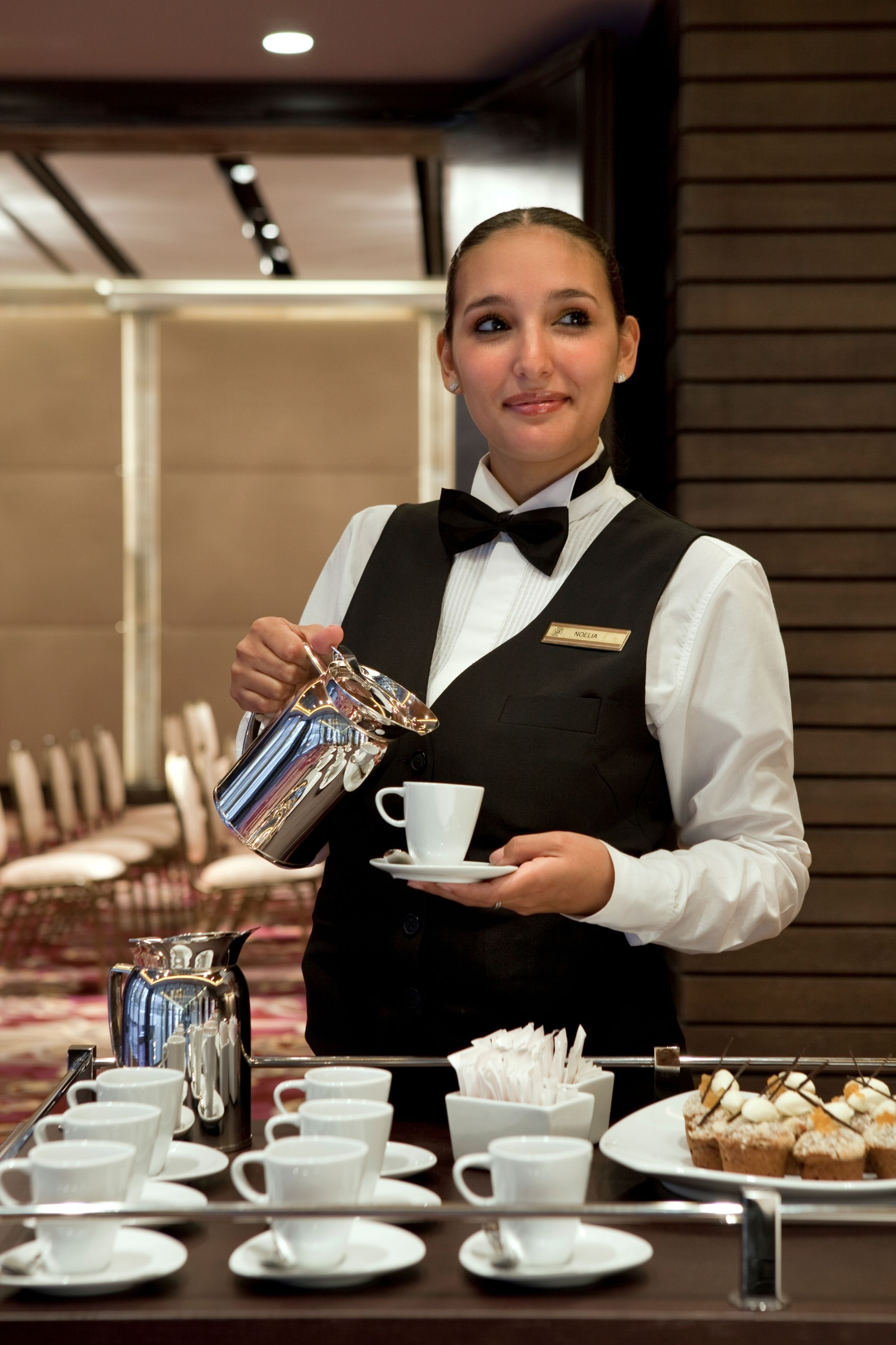 Un empleado de hotel sirve café a un huésped.