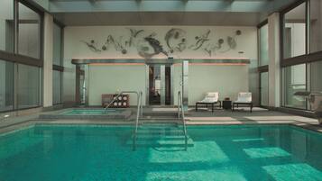 Una piscina con diseño moderno, techo de cristal e instalación artística en la pared.