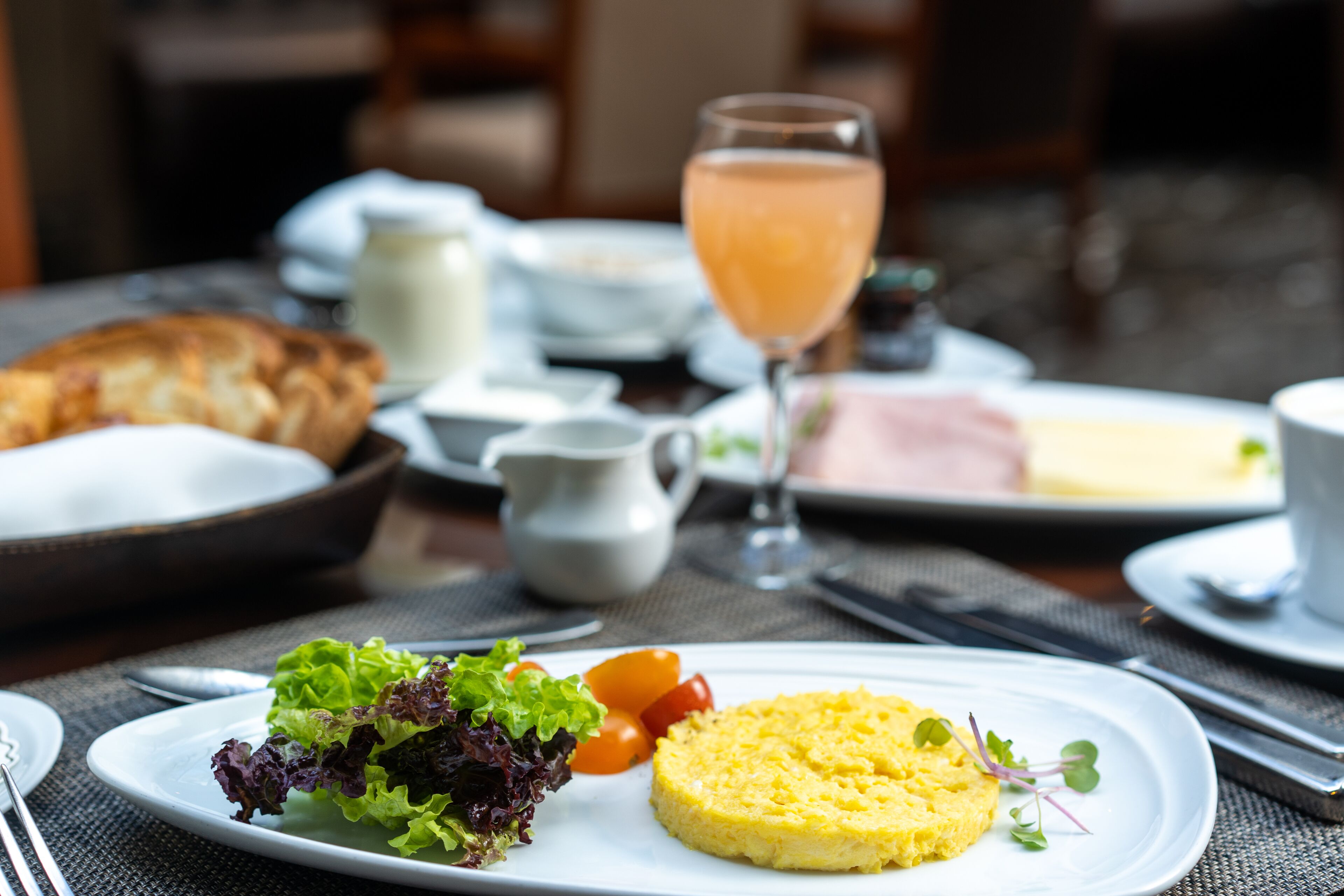 Un desayuno con huevos revueltos, un croissant y un vaso de zumo de naranja.