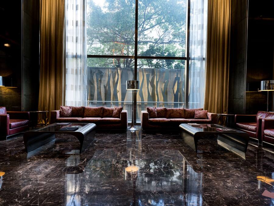 Un hall con sofás de cuero, una mesa de centro de cristal y un suelo de mármol.