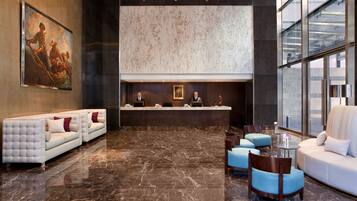 A lobby with a reception desk, plush seating, and a large painting on the wall.