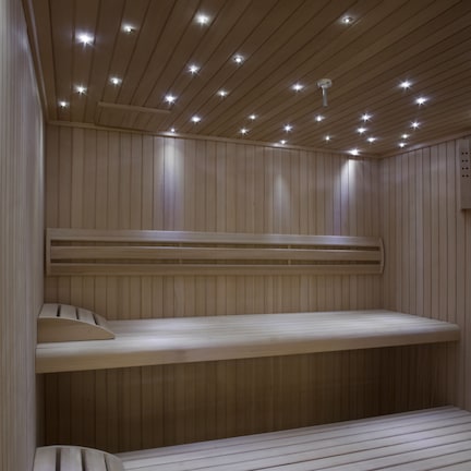 A sauna with wooden benches and a sloped ceiling with recessed lighting.