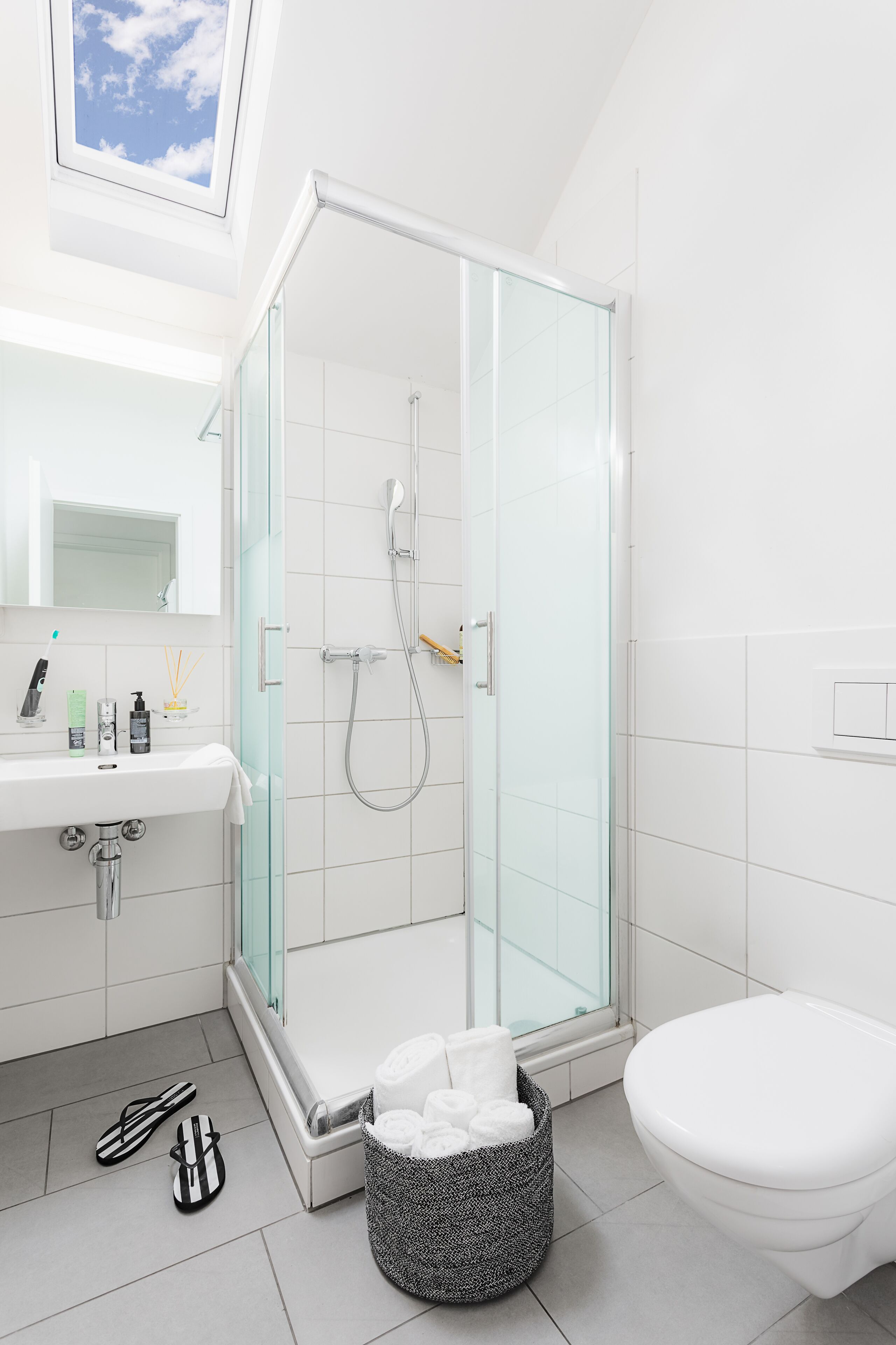 A modern bathroom with a glass-enclosed shower, a white sink, and a toilet.