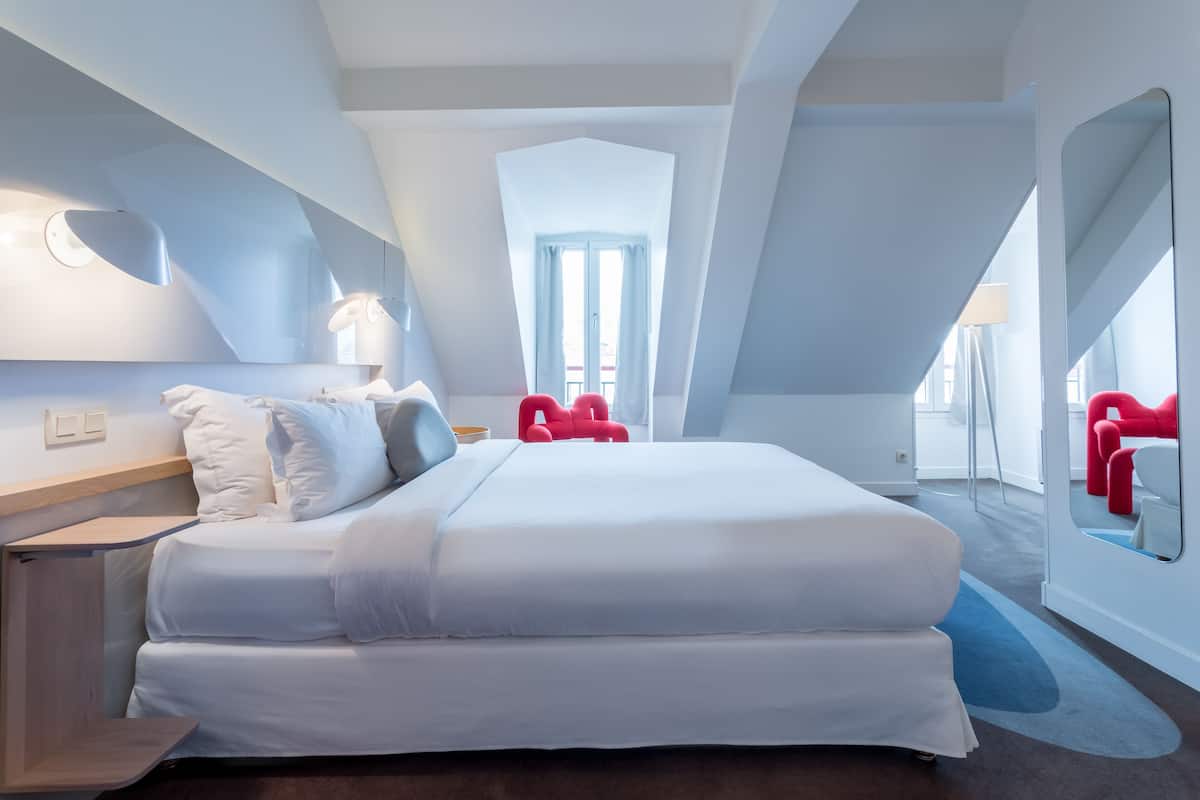 Una habitación de hotel moderna con una cama grande, un escritorio y un espejo.