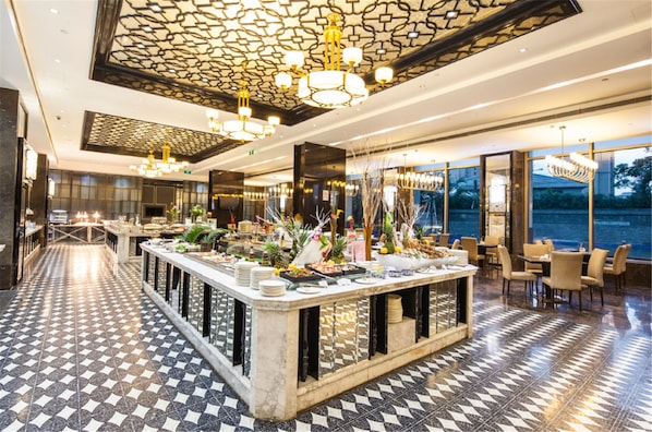 A modern hotel lobby with a checkered floor, a central bar area with various food items, and a large window offering a view of the outdoors. - Ramada Plaza Qiandeng Kunshan (Suzhou)