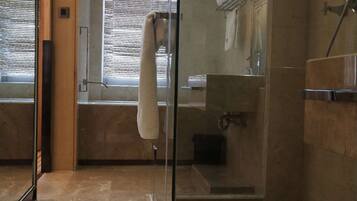 Un baño moderno con cabina de ducha de vidrio, una toalla blanca colgada en la pared y un felpudo en el suelo.
