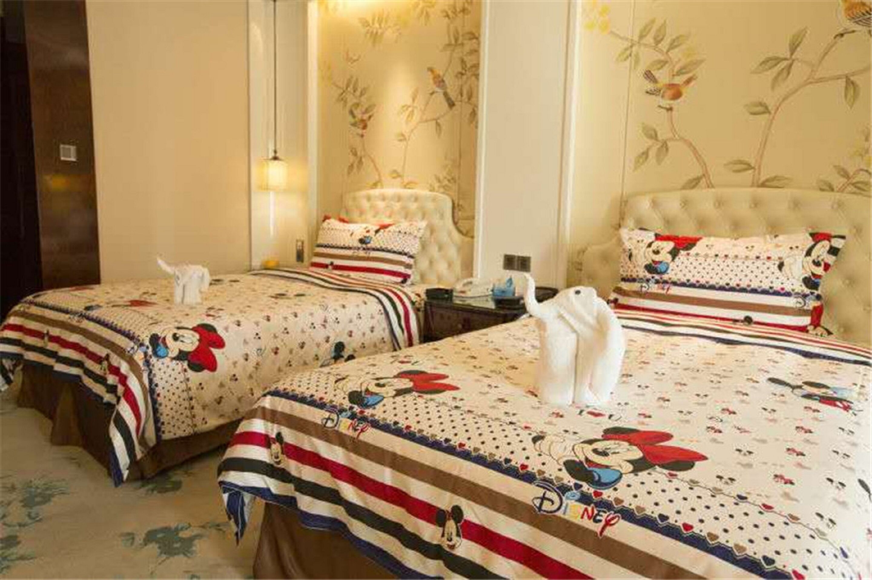 A hotel room with two beds, each adorned with a Mickey Mouse themed bedspread.