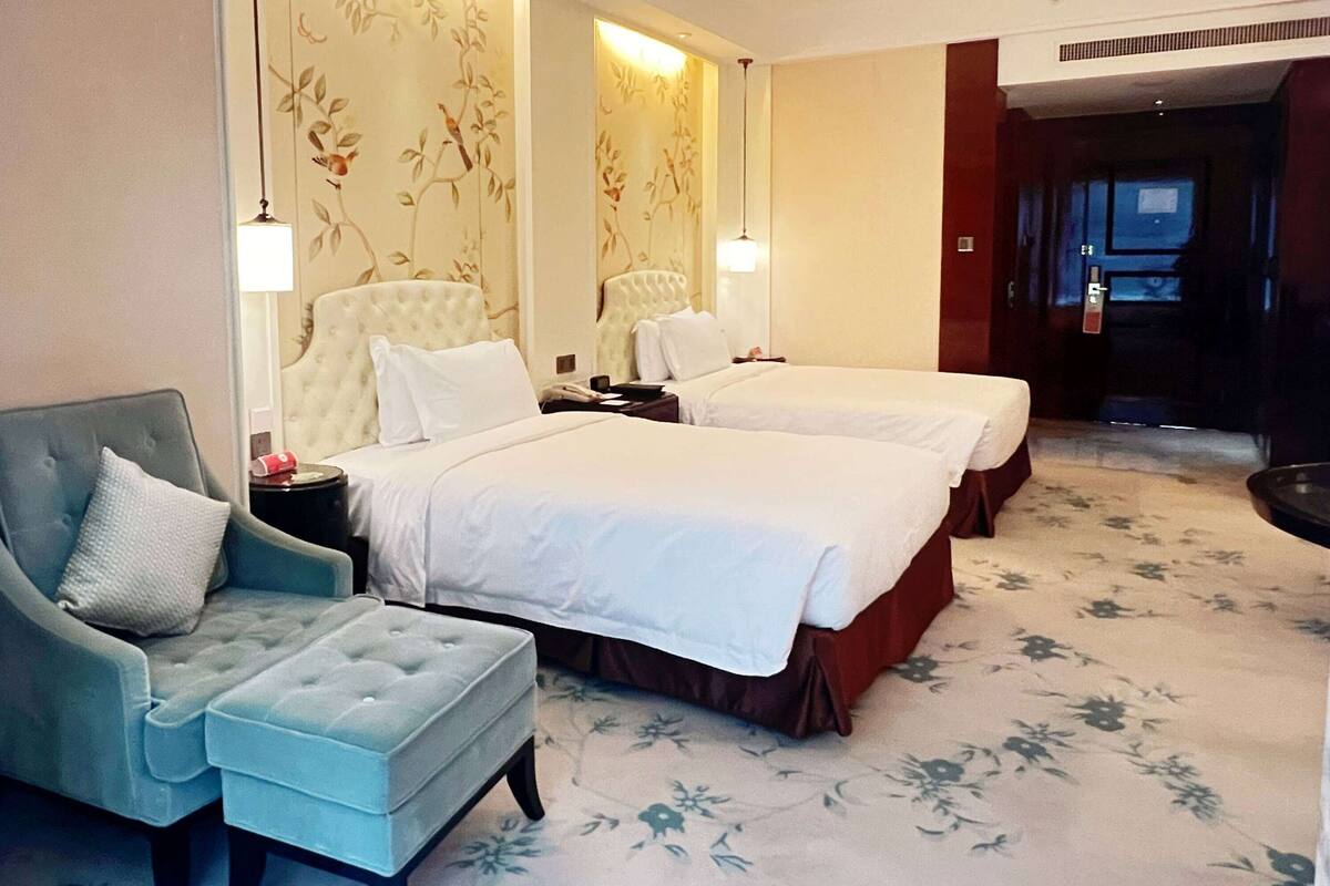 Une chambre d’hôtel avec deux lits, un canapé, une chaise et une petite table.