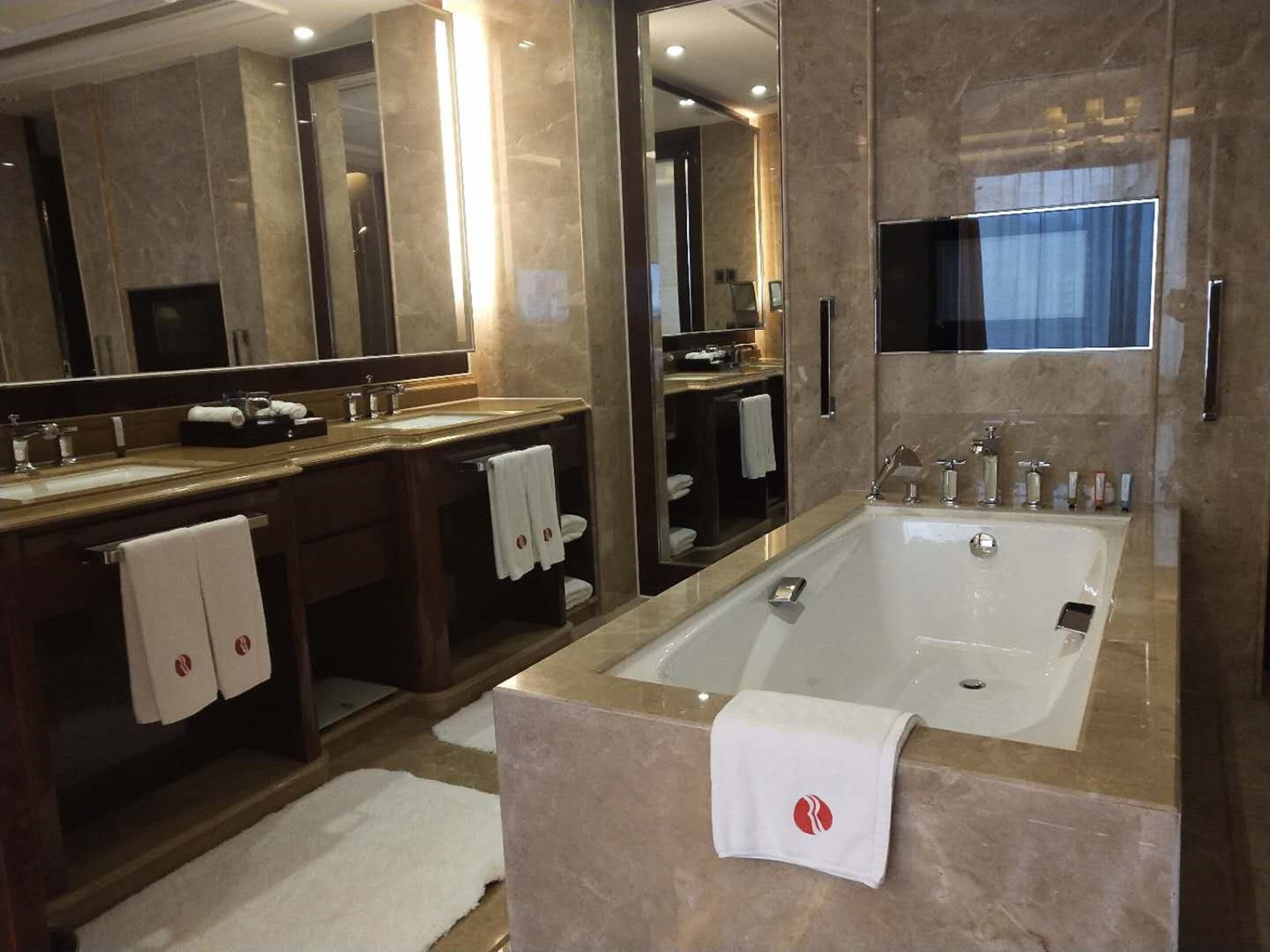 A modern bathroom with a large bathtub, two sinks, and a large mirror.