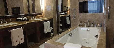 A modern bathroom with a large bathtub, two sinks, and a large mirror.