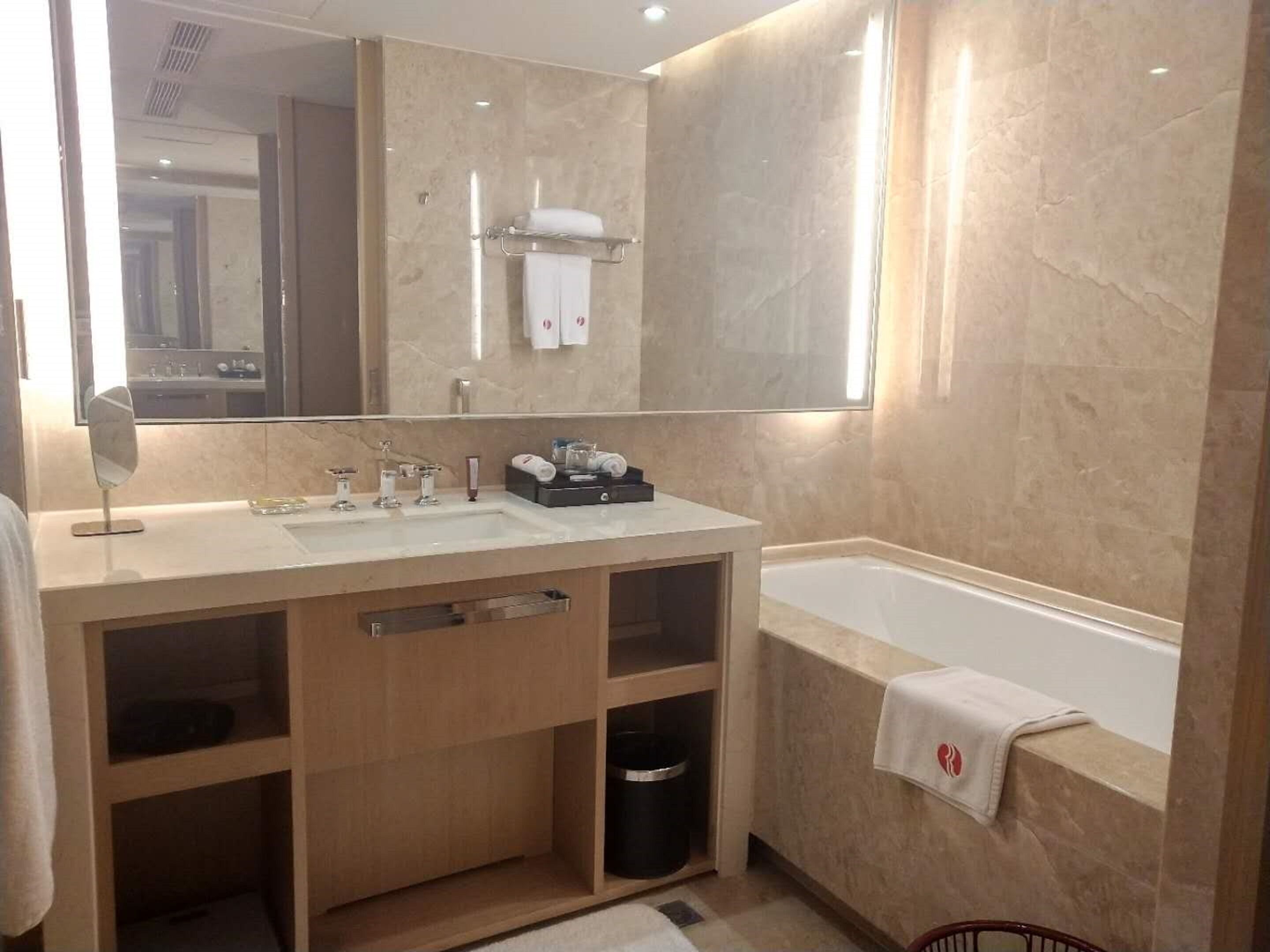Un baño moderno con un espejo grande, un lavabo, una bañera y un mueble de tocador con cajones.