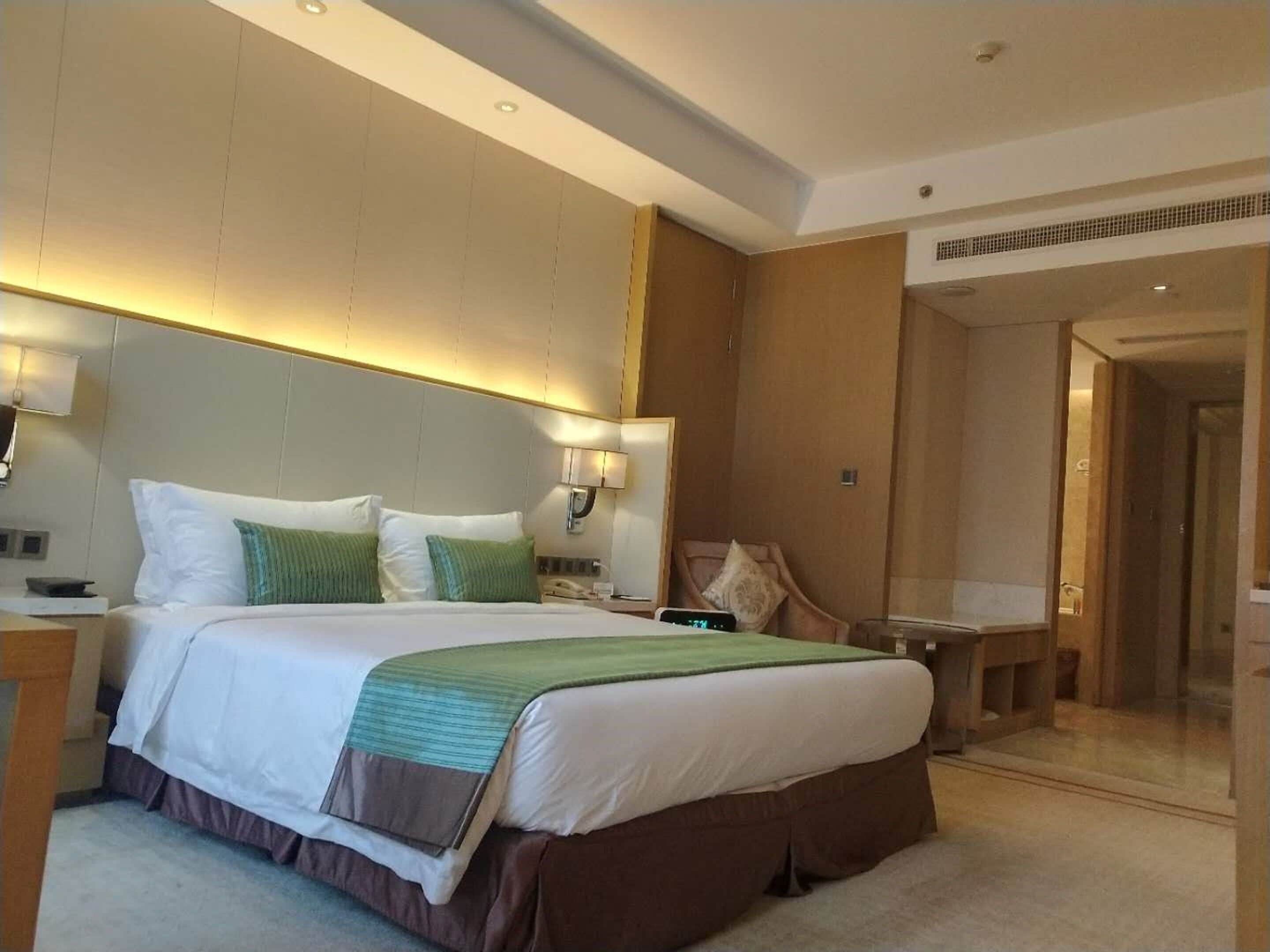 A hotel room with a large bed, bedside tables, a desk, and a chair.