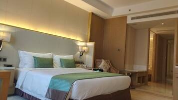 A hotel room with a large bed, bedside tables, a desk, and a chair.