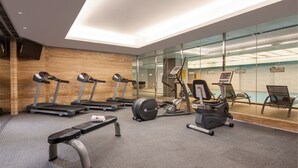 Un gimnasio moderno con cintas de correr, una elíptica, un banco y una máquina de remo.
