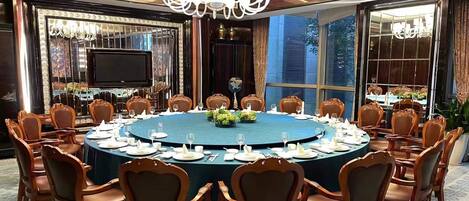 Un salón de conferencias con una mesa redonda, sillas y una araña.