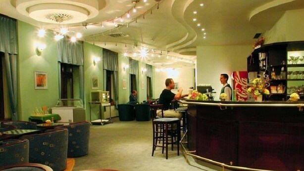 Eine Bar mit Sitzgelegenheiten, einer Theke und einem Barista, der ein Getränk zubereitet.