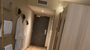 A hallway with a wooden floor, a woven rug, a bamboo ladder, and a wardrobe. - ibis Styles Vannes Porte du Golfe (Vannes)