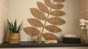 A bathroom with a decorative wall panel, a potted plant, a bottle, and a toothbrush holder. - ibis Styles Vannes Porte du Golfe (Vannes)