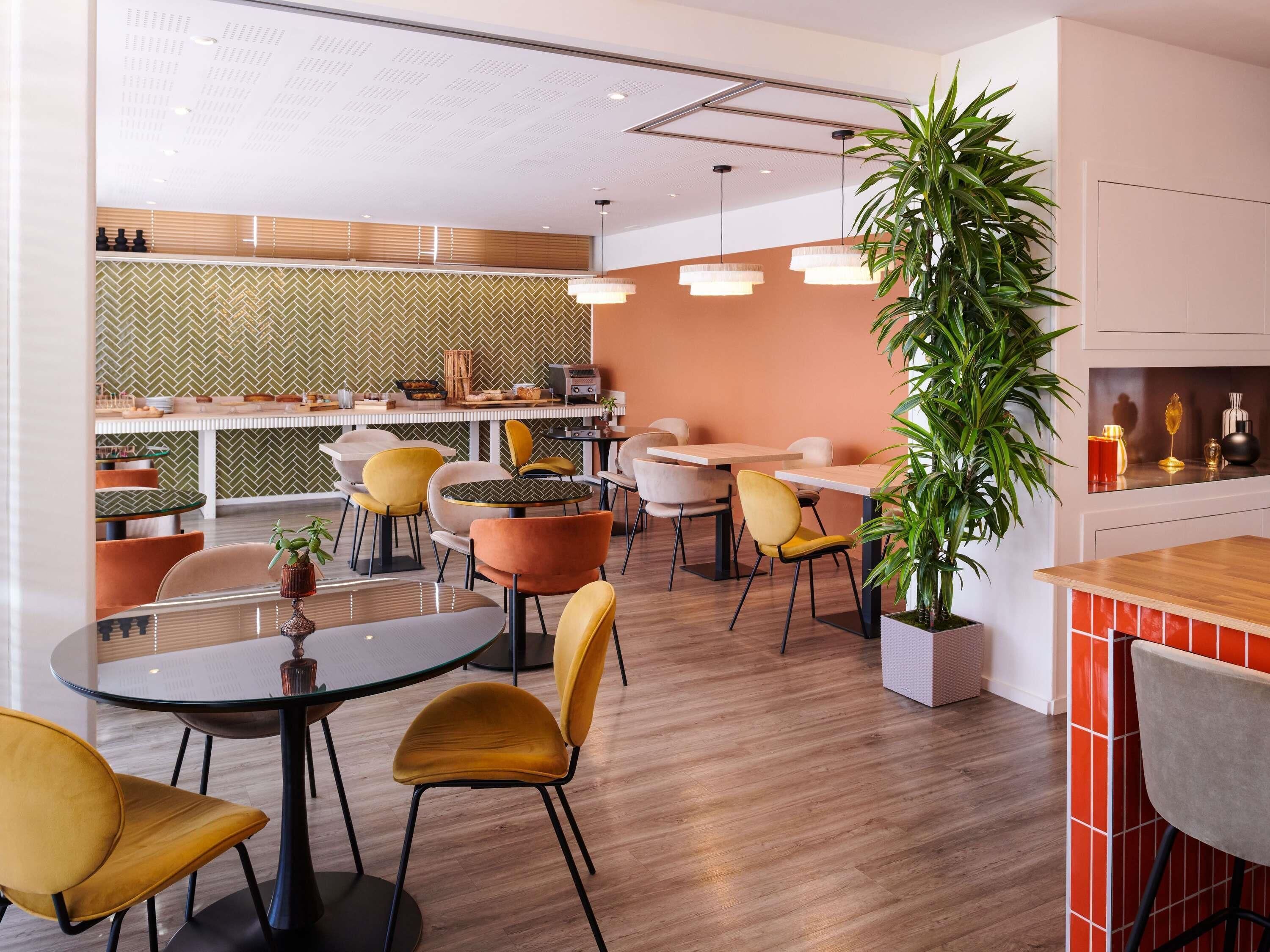 A modern cafe interior with round tables, chairs, and a kitchen area in the background.