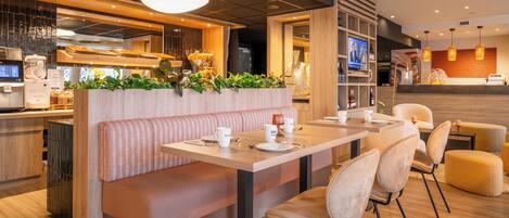 A modern restaurant with a wooden bench seating area, a bar, and a TV screen displaying a program.
