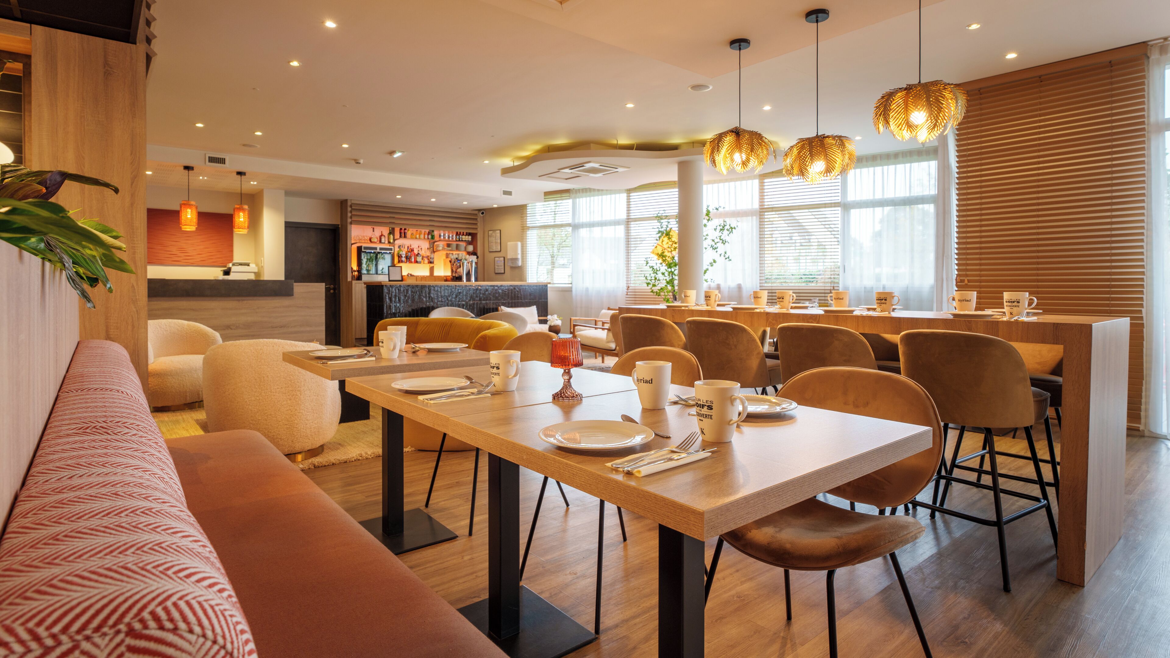 Un comedor moderno con mesas de madera, asientos cómodos e iluminación colgante.