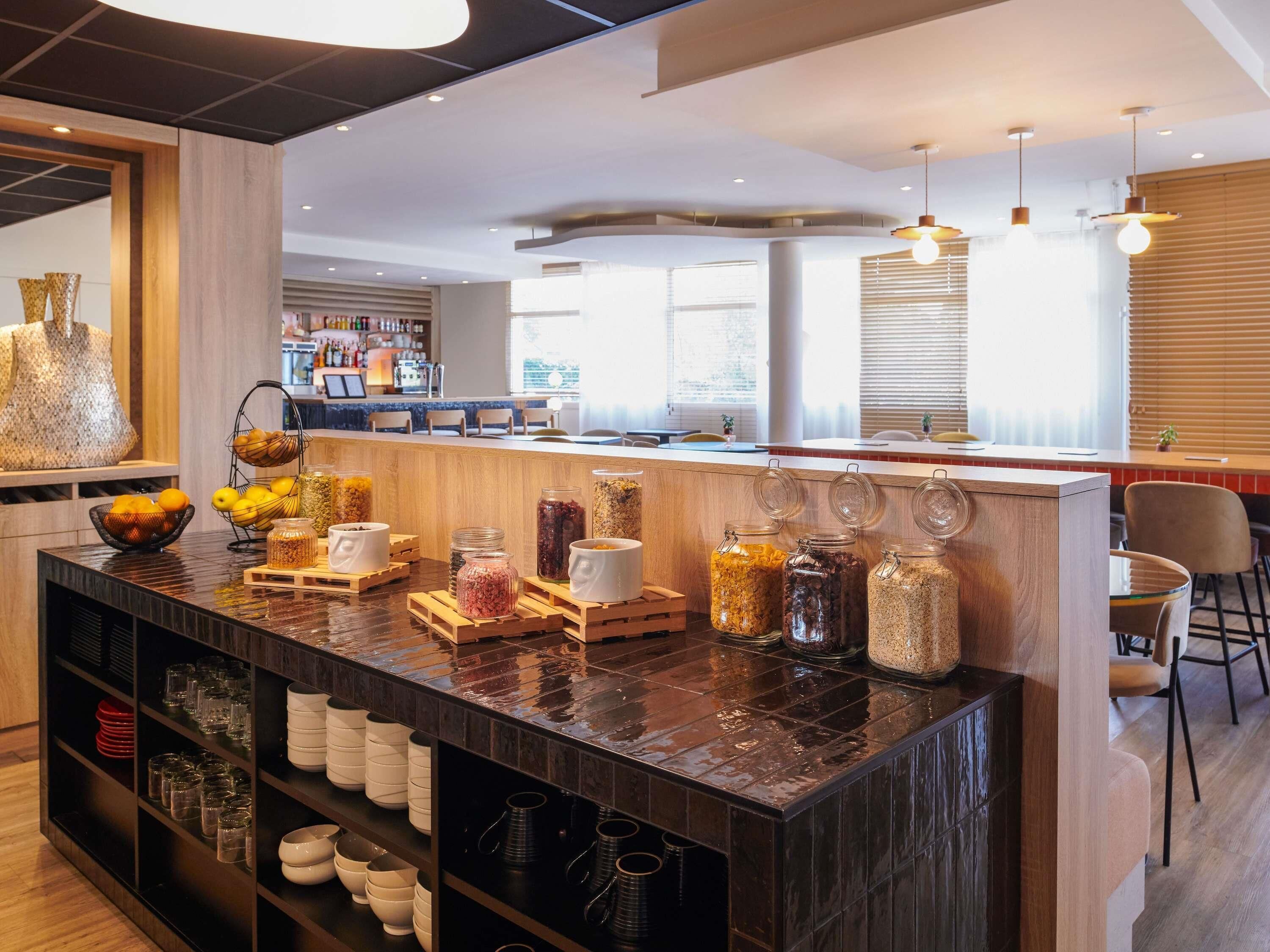 Un bar moderno con mostrador de madera, frascos de condimentos y una zona de estar con sillas.