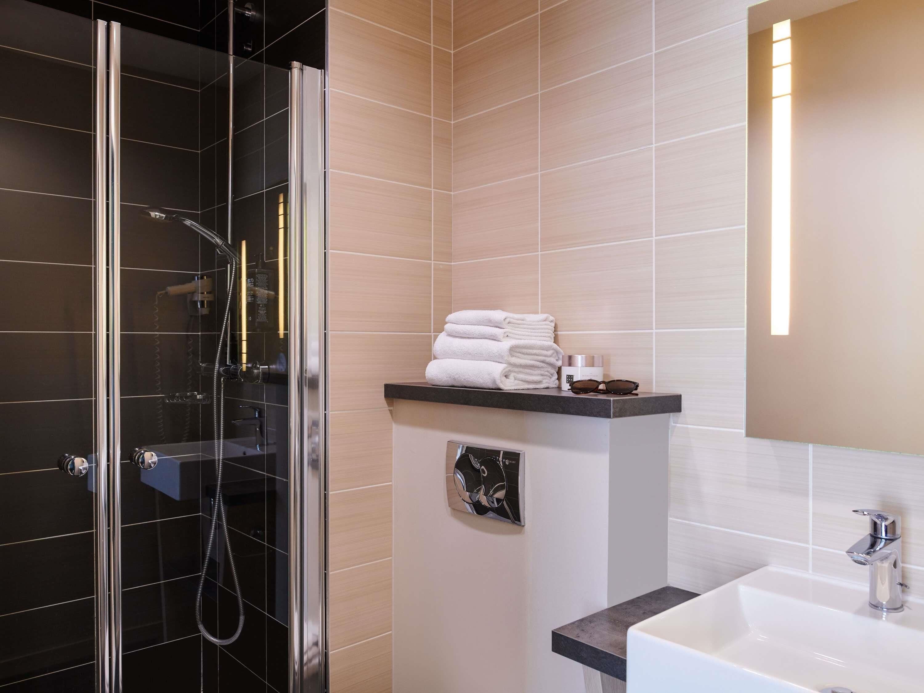 A modern bathroom with a glass-enclosed shower, a sink, and a mirror.