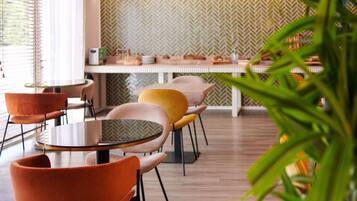 A modern dining area with round tables and chairs, a herringbone-patterned wall, and a wooden floor.