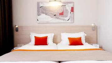 Ein Doppelbett mit weißer und orangefarbener Bettwäsche, ein Holz-Kopfschild und ein an der Wand hängendes abstraktes Gemälde.