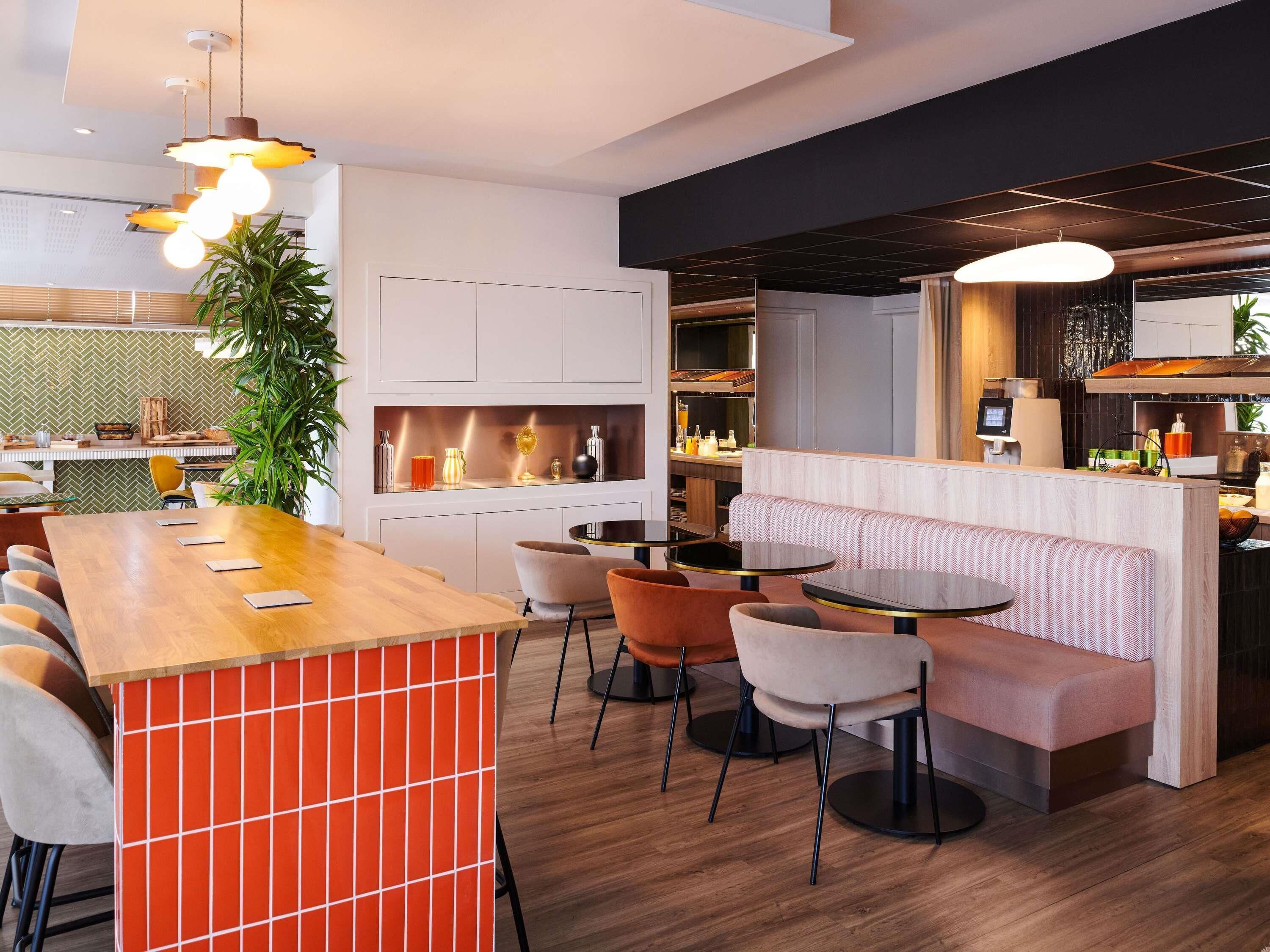 A modern restaurant interior with a bar area, seating, and a kitchen in the background.