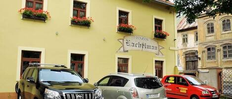 A building with a sign reading "Penzion Kachplumkar" and three parked cars in front.