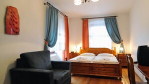 Une chambre à coucher avec un lit en bois, un fauteuil noir et une table de chevet en bois avec une lampe.