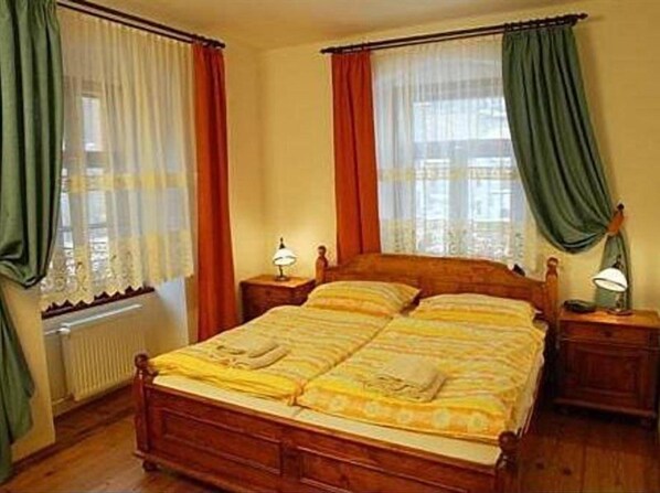 Una cama doble con estructura de madera, dos mesitas de noche con lámparas y un radiador.