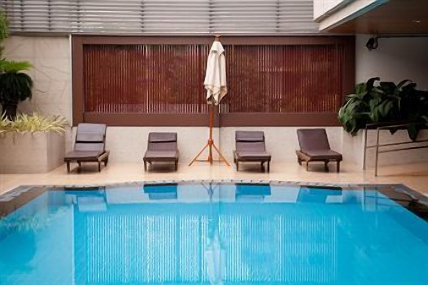 A swimming pool with lounge chairs and a tripod umbrella.